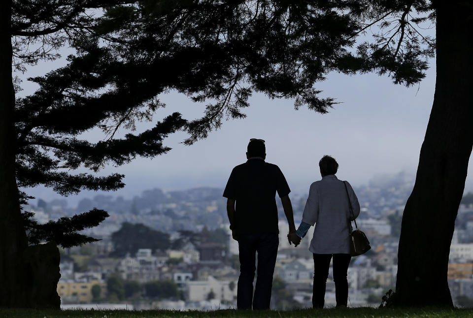 FILE - In this July 3, 2017 file photo, a man and woman walk under trees down a path at Alta Plaza Park in San Francisco. Data from the U.S. Census Bureau shows the median age in the U.S has increased by a year to 38.2 years from 2010 to 2018. The date released Thursday, June 20, 2019, comes as many baby boomers have been hitting the retirement age in recent years.  (AP Photo/Jeff Chiu, File)