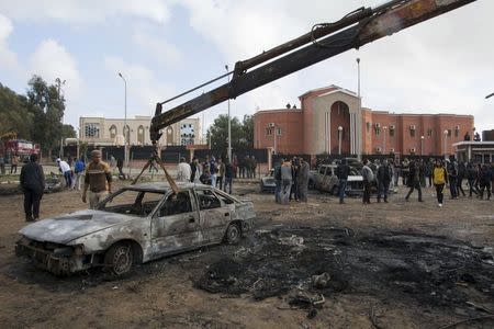 The burnt-out remains of a car is removed from a road at the site of a bomb blast in Shahat, eastern Libya, November 9, 2014. REUTERS/Stringer