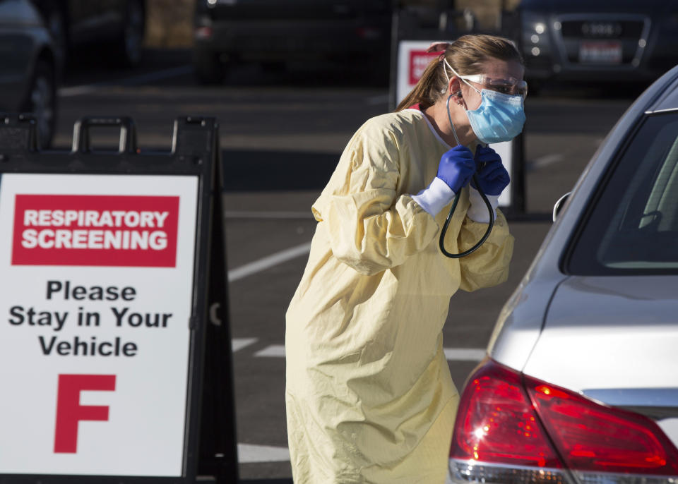FILE - In this Nov. 24, 2020, file photo, physician assistant Nicole Thomas conducts a COVID-19 examination in the parking lot at Primary Health Medical Group's clinic in Boise, Idaho. Arguments over mask requirements and other restrictions have turned ugly in recent days as the deadly coronavirus surge engulfs small and medium-size cities that once seemed a safe remove from the outbreak. (AP Photo/Otto Kitsinger, File)