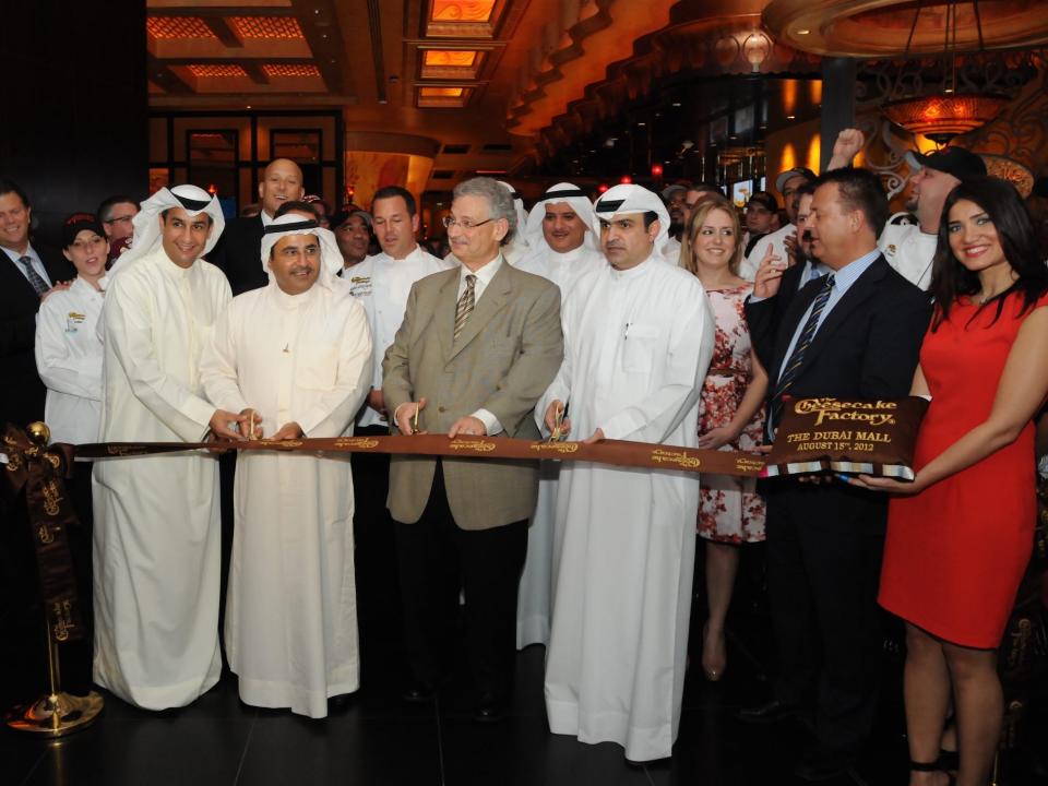 Dubai ribbon cutting - In 2012 The first international Cheesecake Factory restaurant opened in Dubai Mall under a licensing agreement with Alshaya Trading Co., W.L.L