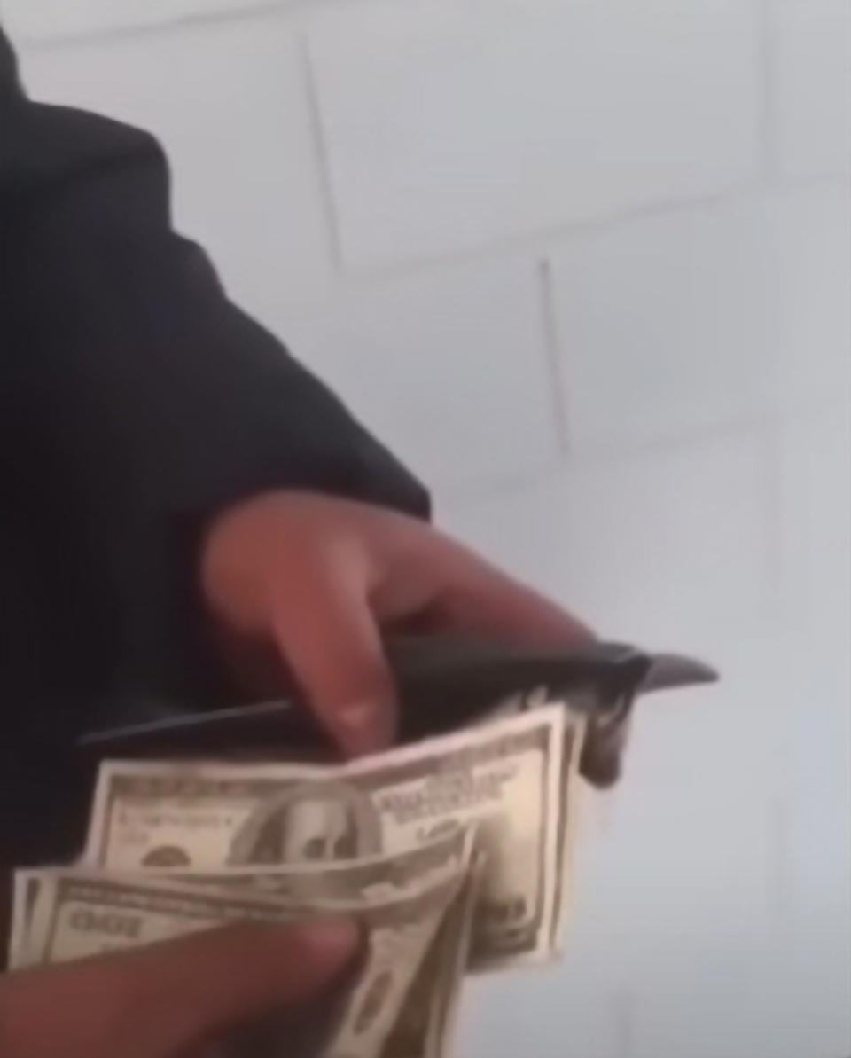 Man holds a bunch of the cash found in the dump. 