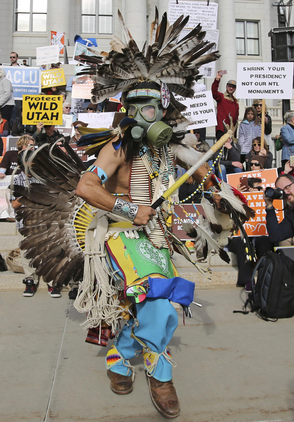 FILE - In this Dec. 2, 2017, photo, a supporter of the Bears Ears and Grand Staircase-Escalante National Monuments wears a colorful headdress during a rally against President Trump's reduction of the two National Monuments in Salt Lake City. The U.S. government is unveiling its final management plan for the national monument on tribal lands home to ancient cliff dwellings and other artifacts in Utah that was significantly downsized by President Donald Trump. Conservation groups, tribes and an outdoor retail company have sued challenging the downsizing. (AP Photo/Rick Bowmer, File)
