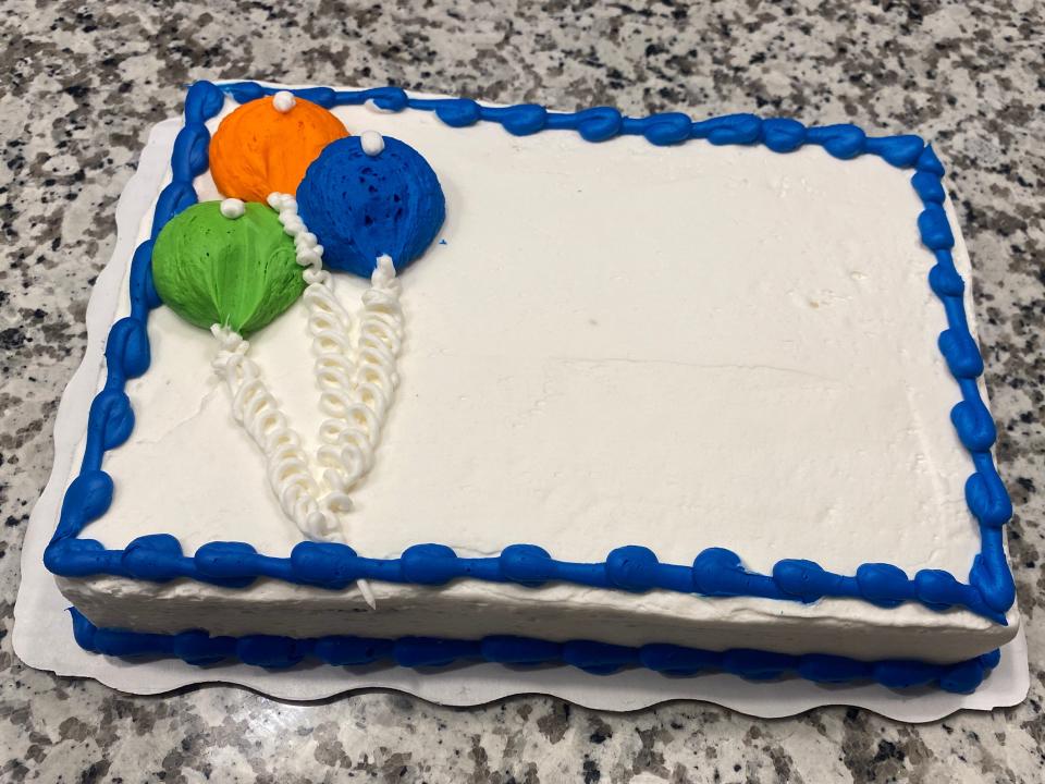 white sheetcake with green, orange, and blue balloons of frosting on the side with a blue border all around