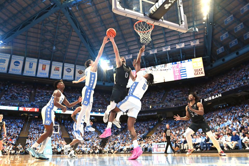 Feb 17, 2024; Chapel Hill, North Carolina, USA; Virginia Tech Hokies guard Hunter Cattoor (0) shoots as North Carolina Tar Heels guard Cormac Ryan (3) and forward Armando Bacot (5) defend in the first half at Dean E. Smith Center. Mandatory Credit: Bob Donnan-USA TODAY Sports