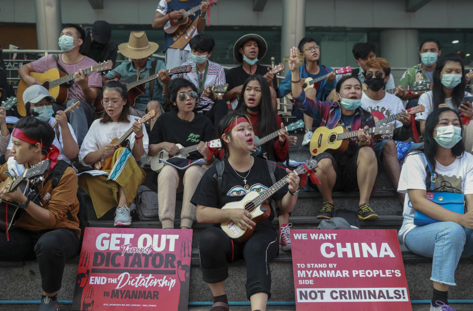 An anti-coup protester flashes the three-fingered salute as others play instruments and sing in Yangon, Myanmar, Tuesday, Feb. 23, 2021. Protesters gathered in Myanmar's biggest city despite the ruling junta's threat to use lethal force against people who join a general strike against the military's takeover three weeks ago. (AP Photo)