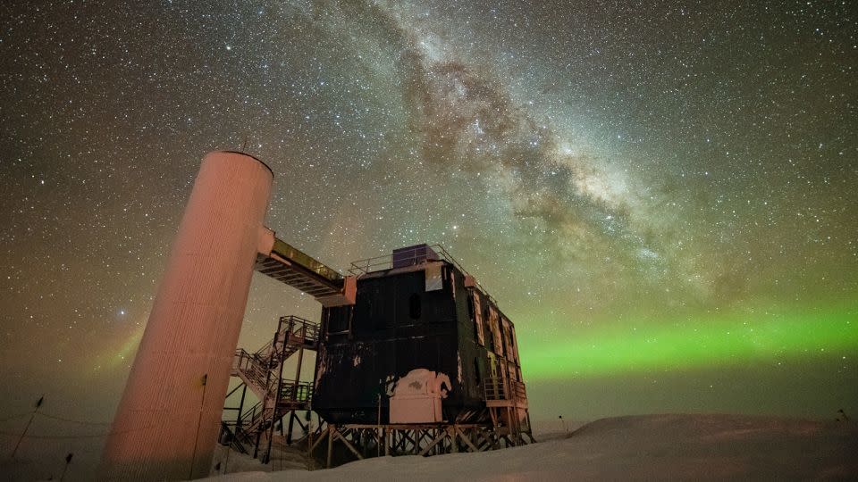 The IceCube detector is seen under a starry night sky, with the Milky Way appearing over low auroras in the background. - Yuya Makino/IceCube/NSF