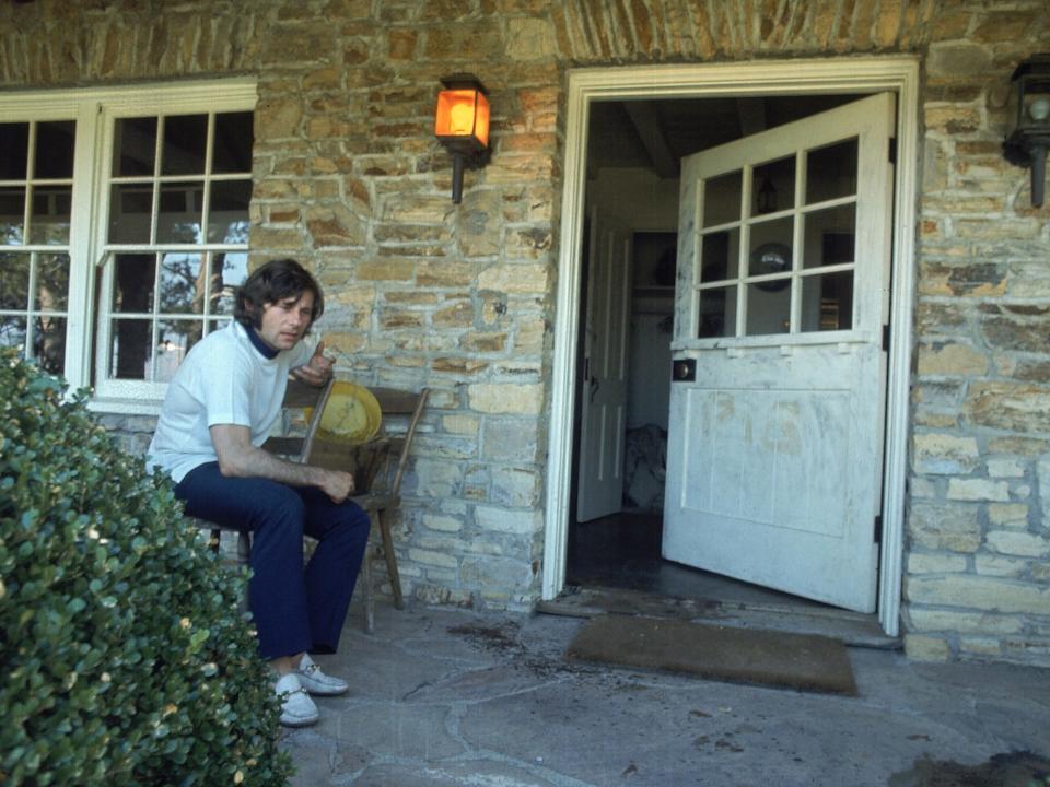 Roman Polanski sitting on bloodied porch outside his home after murder of his wife Sharon Tate and friends by Charles Manson and group. PIG was scrawled on door.