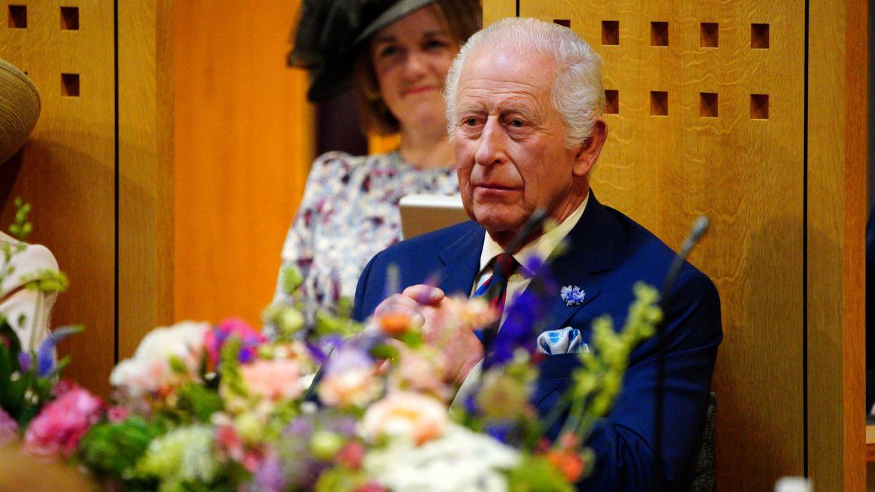 King Charles in a blue suit sat in a wooden chair