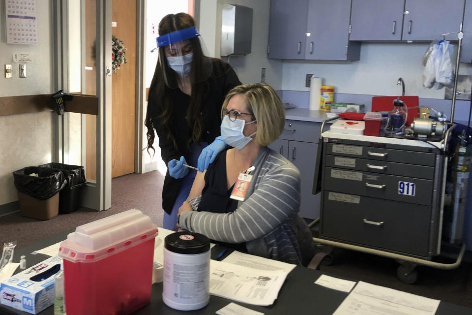 FILE - Cheyenne-Laramie County Health Department nurse Valencia Bautista, left, administers Wyoming's first shot of the Pfizer-BioNTech COVID-19 vaccine on Dec. 15, 2020, to Terry Thayn, who is also a nurse for the department, in Cheyenne, Wyo. The U.S. is in better shape approaching its second Thanksgiving in a pandemic, thanks to vaccines, though some regions are reporting torrents of COVID-19 cases that could get even worse in the days ahead as eager families travel the country for overdue gatherings that were impossible a year ago. (AP Photo/Mead Gruver, File)