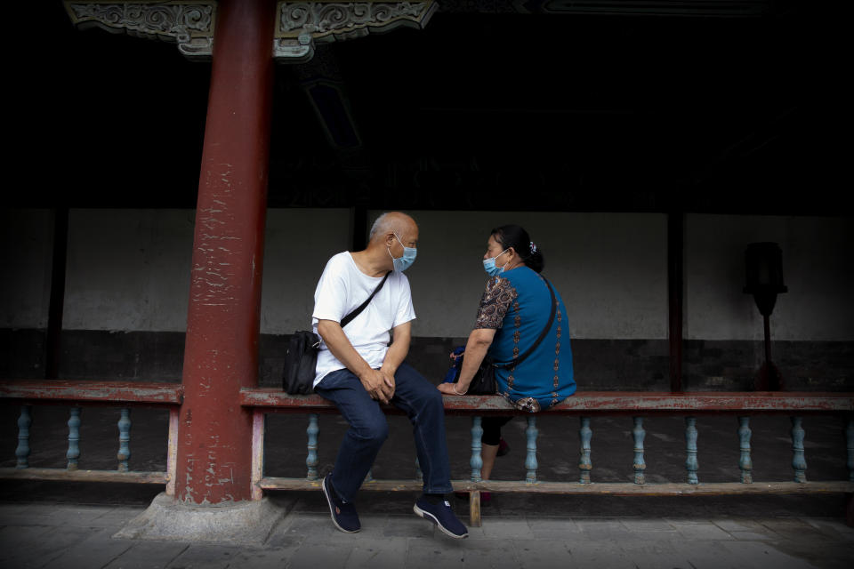 People wearing face masks to protect against the coronavirus sit on a railing at the Temple of Heaven in Beijing, Saturday, July 18, 2020. Authorities in a city in far western China have reduced subways, buses and taxis and closed off some residential communities amid a new coronavirus outbreak, according to Chinese media reports. They also placed restrictions on people leaving the city, including a suspension of subway service to the airport. (AP Photo/Mark Schiefelbein)