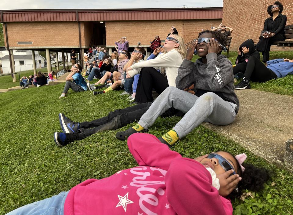 (Lying in front) Tinslee Armstrong, 9, a fourth grade student at Riverside Elementary reclines on the school lawn as she watches the different phases of the partial eclipse with classmates Amir Kafi and Avery McDonald on April 8, 2024 in Columbia, Tenn.