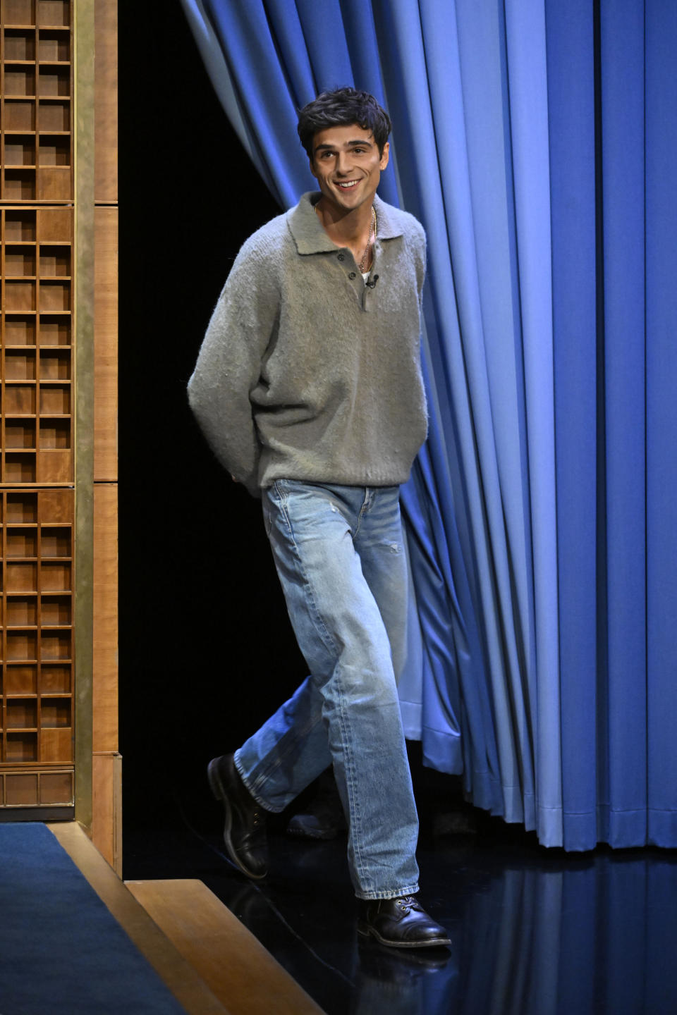 Jacob Elordi onstage next to a blue curtain.