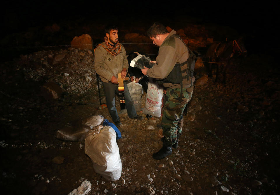 In this picture taken on early Sunday, April 20, 2014, a Lebanese army soldier searches the belongings of a Syrian man who fled from the village of Beit Jinn near the Israeli-occupied Golan Heights, after he descended from the 2,814-meter (9,232-foot) Mount Hermon (Jabal el-Sheikh), into the town of Chebaa in southeast Lebanon. The soldiers are particularly suspicious of young men, like 28-year-old Saleh Zawaraa, who was wrapped in bandages. He told the soldiers he was not a fighter, but was hit by a tank shell outside of Beit Jinn while trying to bring bread into the village. The soldiers let him through.(AP Photo/Hussein Malla)