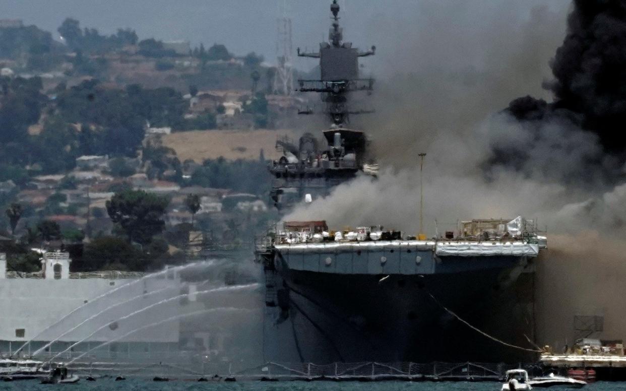 Firefighting boats spray water onto the US Navy amphibious assault ship USS Bonhomme Richard as smoke rises from a fire - Bing Guan/Reuters