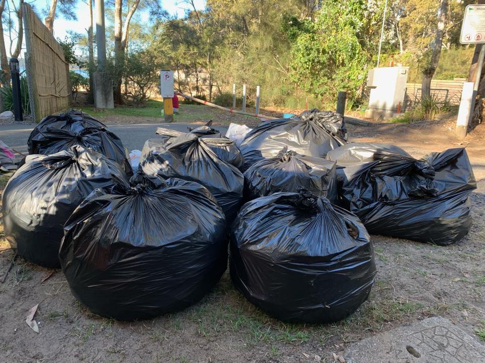 Photo shows several black plastic garbage bags containing the rubbish collected on the beach.