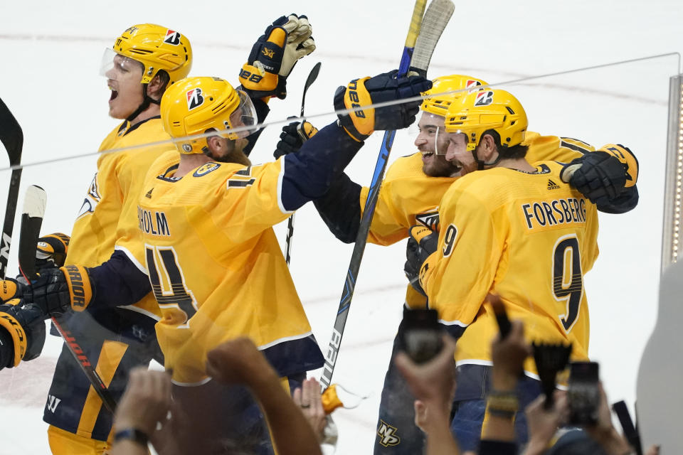 Nashville Predators center Luke Kunin, second from right, celebrates with Mattias Ekholm (14) and Filip Forsberg (9) after Kunin scored the winning goal against the Carolina Hurricanes during the second overtime in Game 4 of an NHL hockey Stanley Cup first-round playoff series Sunday, May 23, 2021, in Nashville, Tenn. The Predators won 4-3 to even the series 2-2. (AP Photo/Mark Humphrey)