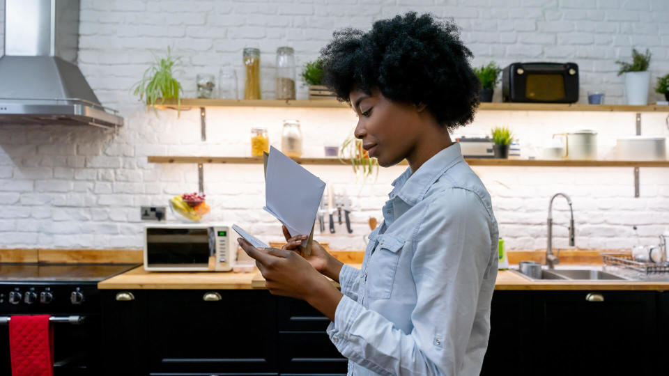 Portrait of a African American woman at home reading the mail - lifestyle concepts.