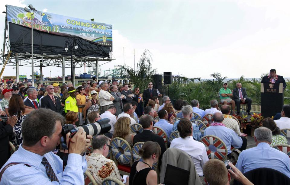 A sign is unveiled as New Jersey Gov. Chris Christie, right, addresses a gathering on the Boardwalk in Atlantic City, N.J., Monday, July, 24, 2012 after it was announced that singer Jimmy Buffett is teaming up with Resorts Casino Hotel to bring one of his Margarativille casino-entertainment complexes to Atlantic City. The project will be built as an addition to the Resorts Casino Hotel. (AP Photo/Mel Evans)