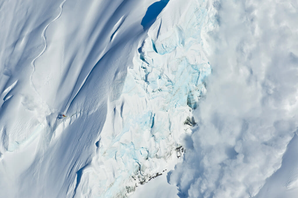 Bjorn Leines snowboards in Valdez, Alaska, right next to a massive serac. An avalanche is on the right. (Photo by Darcy Bacha, via Getty Images)