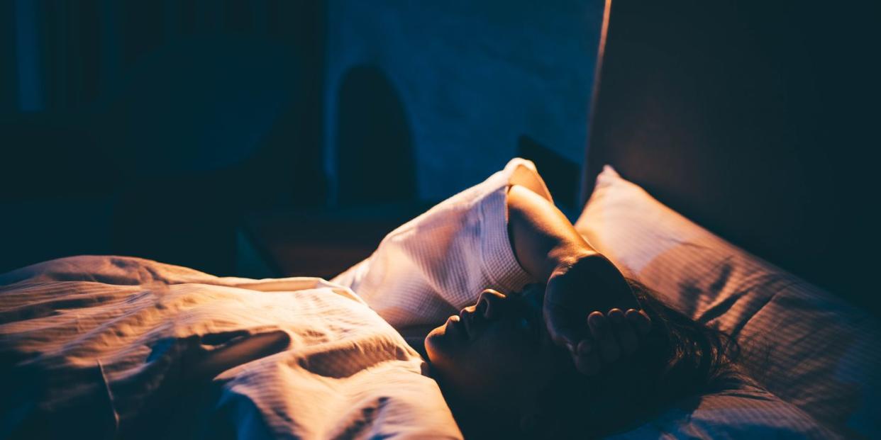 woman with insomnia young woman lying on bed with hand on forehead