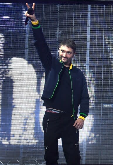 Tom Parker onstage holding a microphone up in the air