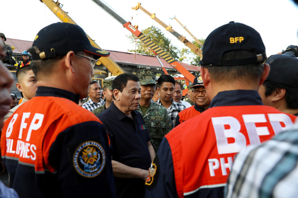 In this April 23, 2019, photo released by the Malacanang Presidential Photographers Division, Philippine President Rodrigo Duterte, center, talks to rescuers as he visits an earthquake-damaged building where operations continue for trapped people in Porac town, Pampanga province, northern Philippines. The Philippine national police chief says investigators have summoned the owner of a four-story supermarket that collapsed in a powerful earthquake and trapped dozens of people. (Richard Madelo/Malacanang Presidential Photographers Division via AP)