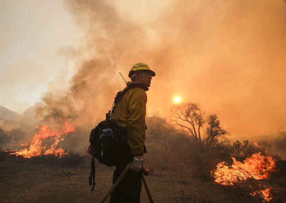 <p>A firefighter looks on as the flames lick the mountainside. (AP Photo/Ringo H.W. Chiu)</p>