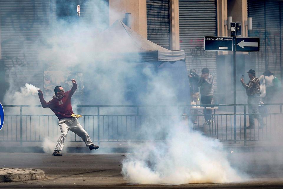 A demonstrator throws a tear gas canister during clashes between protesters and police (AFP via Getty Images)