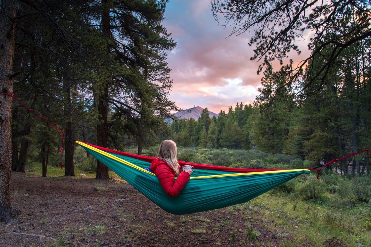 A woman using a portable hammock in the forest