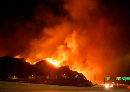 A wind-driven wildfire burns near power line tower in Sylmar, California