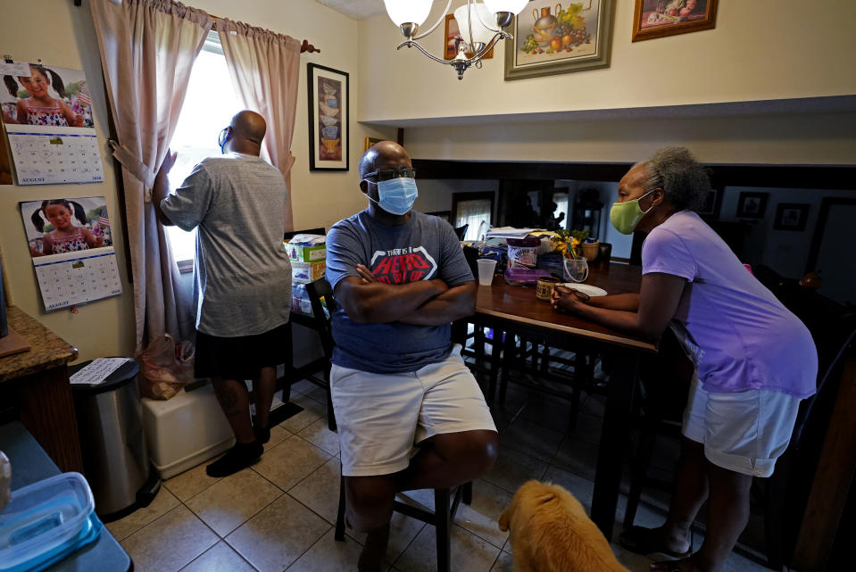 Larry Brown, left, talks with his parents John and Marilyn Brown as Larry cooks dinner, Thursday, Aug. 27, 2020, in Indianapolis. Larry doesn’t know why his father’s case was comparatively mild, as John Brown spent seven days on a ventilator _ about 40 less than his son. Marilyn ended up with a mild case. (AP Photo/Darron Cummings)