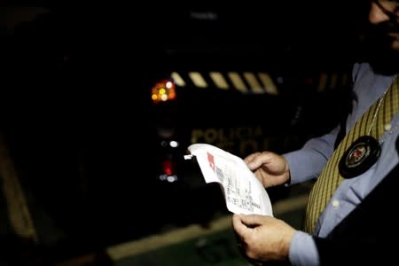 A police officer looks at a tracking slip found inside a pickup truck used during the theft at Guarulhos airport in Sao Paulo