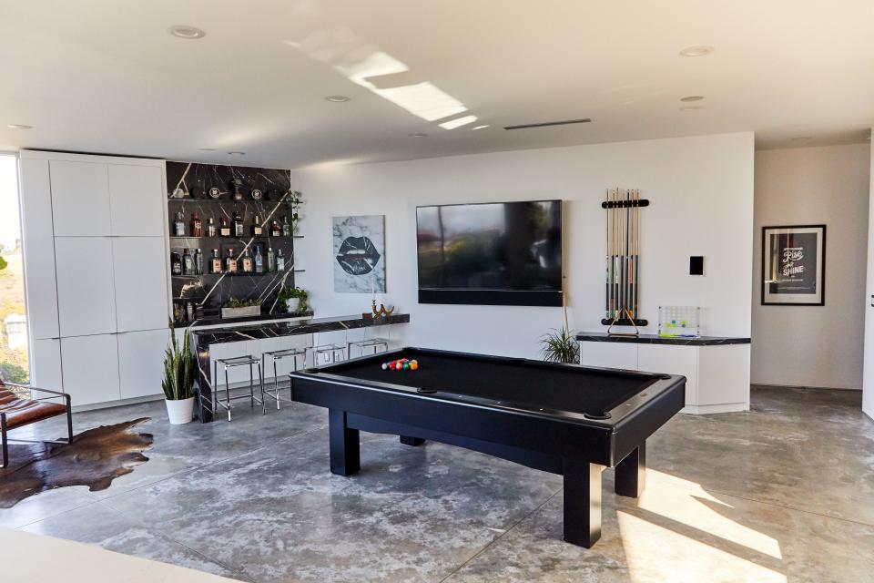 During the remodel, the space that was being used as the living room became Huston’s entertainment room, complete with a pool table from his previous home that he re-covered in black felt, and a new black marble bar featuring slabs he hand-selected. “I haven’t had an official party here, but it’s definitely a good room for entertaining,” says the billiards enthusiast.