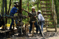 Oil well workers prepare to plug an orphaned well on the Rooke family ranch, Tuesday, May 18, 2021, near Refugio, Texas. Oil and gas drilling began on the ranch in the 1920s and there were dozens of orphaned wells that needed to be plugged for safety and environmental protection. (AP Photo/Eric Gay)