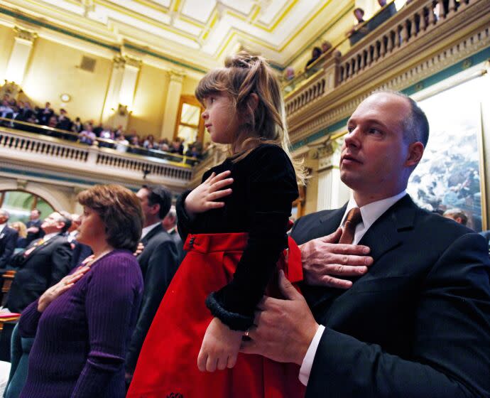 Rep. Kevin Priola, R-Henderson, holds his daughter Bremma, 5, during the singing of the National Anthem during the opening session of the Legislature at the Capitol in Denver on Wednesday, Jan. 12, 2011.(AP Photo/Ed Andrieski)