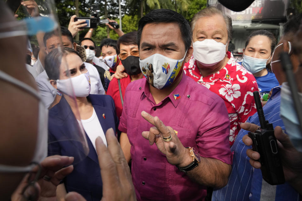 Retired Filipino boxing hero and senator Manny Pacquiao, center, talks to police beside wife Jinkee, left, before filing his certificate of candidacy for next year's presidential elections at the Commission on Elections on Friday, October 1, 2021 in Manila, Philippines. Friday marks the first day of a week-long period when politicians can file their certificates of candidacy for the May 9, 2022 national elections where Filipinos will get to vote for their next president, vice president, and other national and local officials.(AP Photo/Aaron Favila)