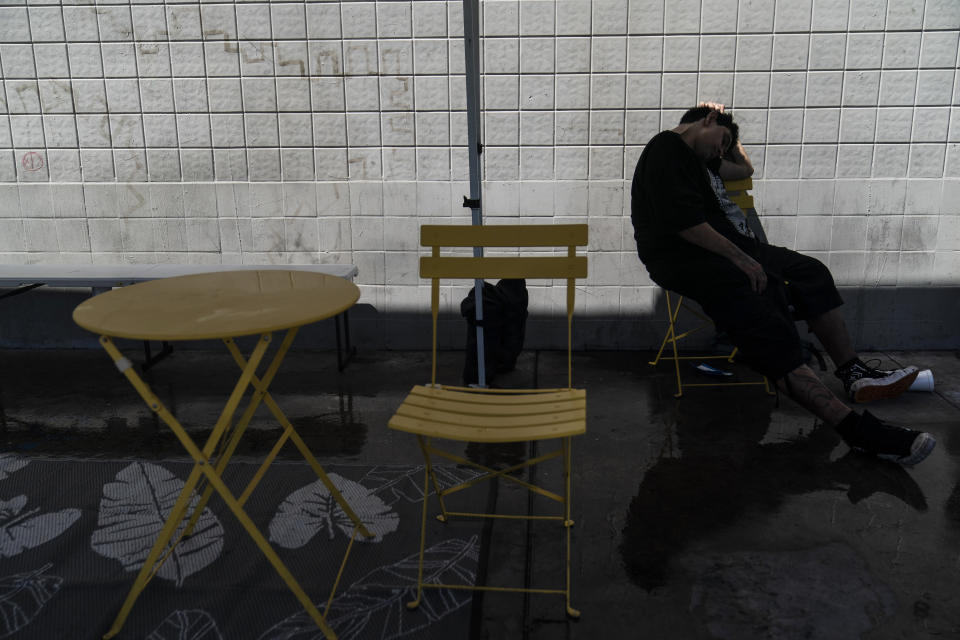A man naps under a mist tent in the Skid Row area of Los Angeles, Wednesday, Aug. 31, 2022. Excessive-heat warnings expanded to all of Southern California and northward into the Central Valley on Wednesday, and were predicted to spread into Northern California later in the week. (AP Photo/Jae C. Hong)