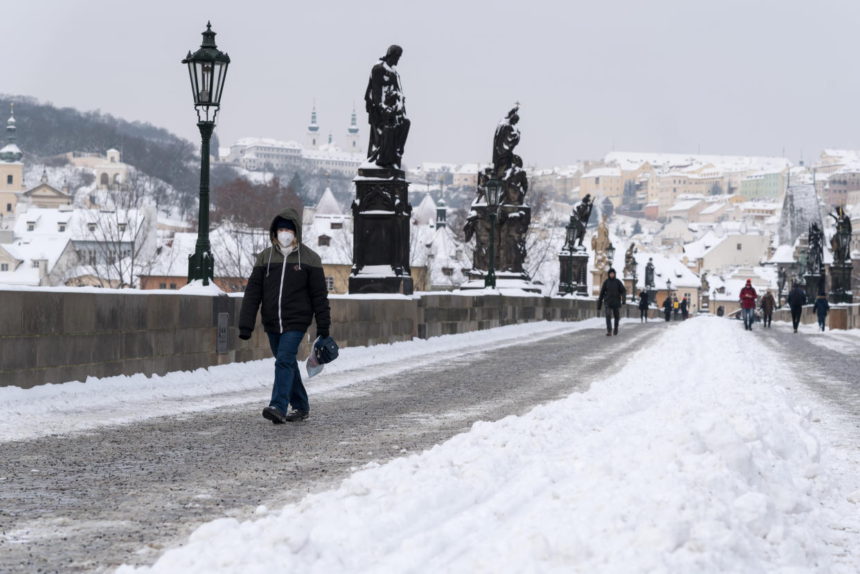 A woman wearing a facemask as a preventive measure against the spread of coronavirus, walks on the iconic Charles Bridge. Heavy snowfall across the Czech Republic has disrupted rail, road and public transport. (Photo by Tomas Tkacik / SOPA Images/Sipa USA)