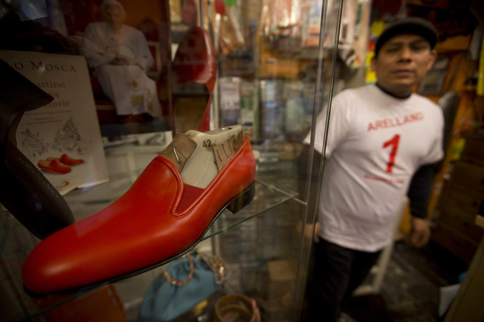 Antonio Arellano stands next to a copy of a pair of shoes he made for Pope Benedict XVI, in his shoemaker shop, in Rome, Monday, March 18, 2013. Borgo, the sleepy, medieval neighborhood with a timeless feel right outside the Vatican's borders, has been at the service of pontiffs for centuries. From resoling to risotto, from light bulbs to linguine, Borgo is the go-to place for up-and-coming cardinals and sometimes even for popes. (AP Photo/Andrew Medichini)