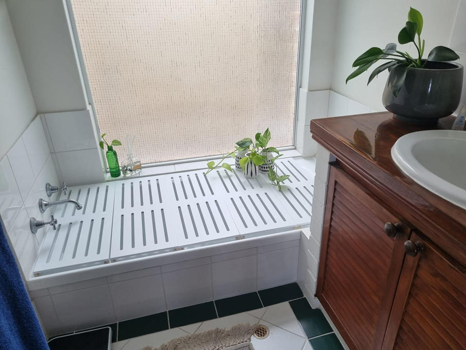 Photo of a bathroom showing two Kmart shoe racks sitting inside a bathtub