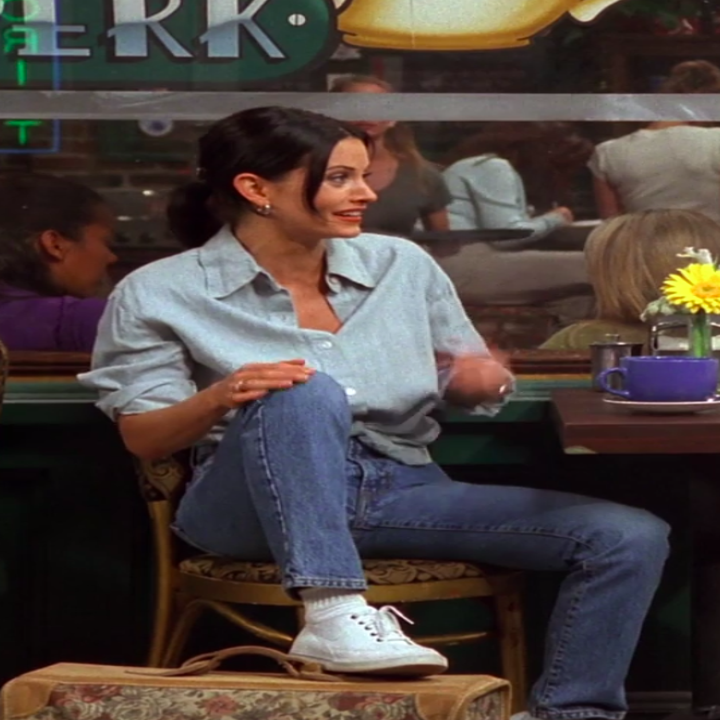 Monica wearing sneakers, jeans, and a tied button-up