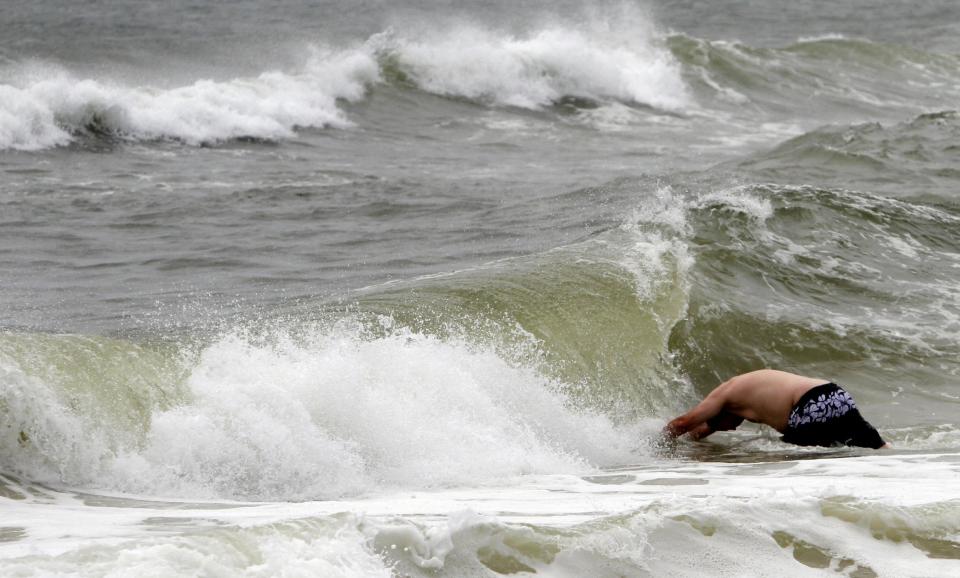 A man dives into a large wave caused by Tropical Storm Isaac in Gulf Shores, Ala. on Monday, Aug. 27, 2012. The National Hurricane Center predicted Isaac would grow to a Category 1 hurricane over the warm Gulf and possibly hit late Tuesday somewhere along a roughly 300-mile (500-kilometer) stretch from the bayous southwest of New Orleans to the Florida Panhandle. The size of the warning area and the storm's wide bands of rain and wind prompted emergency declarations in four states, and hurricane-tested residents were boarding up homes, stocking up on food and water or getting ready to evacuate. (AP Photo/Butch Dill)