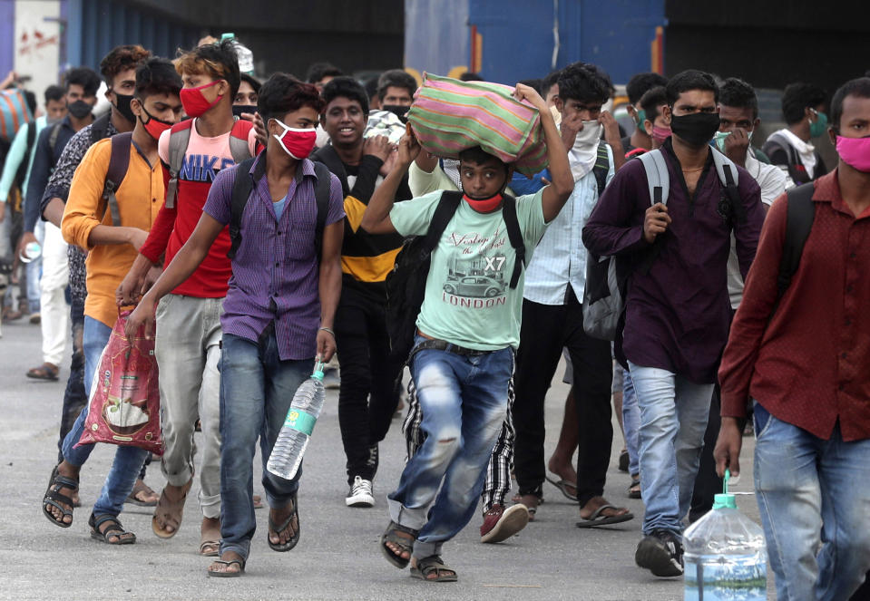 In this Friday, May 15, 2020, photo, migrant workers from other Indian states run towards a railway station desperate to catch a train to return to their homes, in Mumbai, India. Tens of thousands of impoverished migrant workers are on the move across India, walking on highways and railway tracks or riding trucks, buses and crowded trains in blazing heat amid threat to their lives from the coronavirus pandemic. (AP Photo/Rafiq Maqbool)