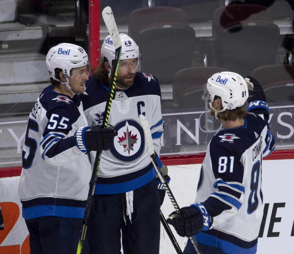 Winnipeg Jets' Mark Scheifele, left, and Kyle Connor, right, congratulate Blake Wheeler on his goal against the Ottawa Senators during the second period of an NHL hockey game Thursday, Jan. 21, 2021, in Ottawa, Ontario. (Adrian Wyld/The Canadian Press via AP)