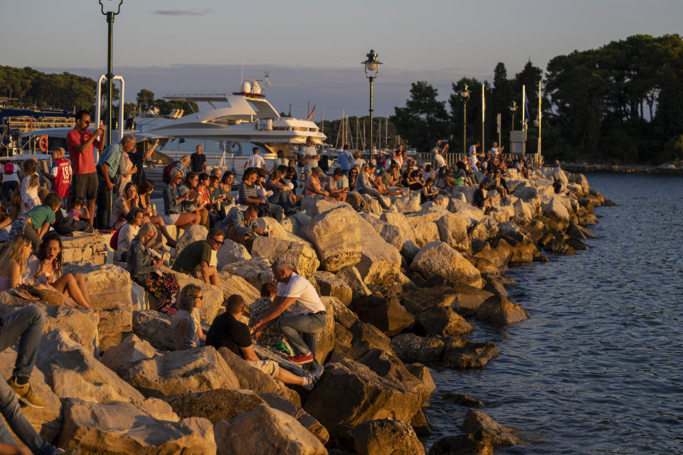 Holidaymakers enjoy sunset on the seafront in the Adriatic town of Rovinj, Croatia, Friday, Aug. 27, 2021. Summer tourism has exceeded even the most optimistic expectations in Croatia this year. Beaches along the country's Adriatic Sea coastline are swarming with people. Guided tours are fully booked, restaurants are packed and sailboats were chartered well in advance. (AP Photo/Darko Bandic)