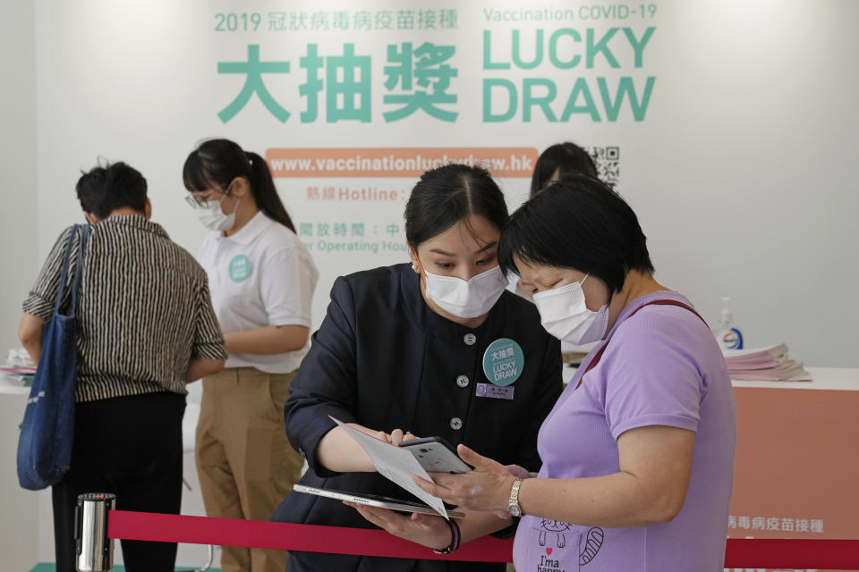 In this Tuesday, June 15, 2021, photo, people wearing face masks to help prevent the spread of the coronavirus, register for a lottery in a Grand Central residential building complex in Hong Kong. Coronavirus vaccine incentives offered by Hong Kong companies, including a lucky draw for an apartment, a Tesla car and even gold bars, are helping boost the city’s sluggish inoculation rate. (AP Photo/Kin Cheung)