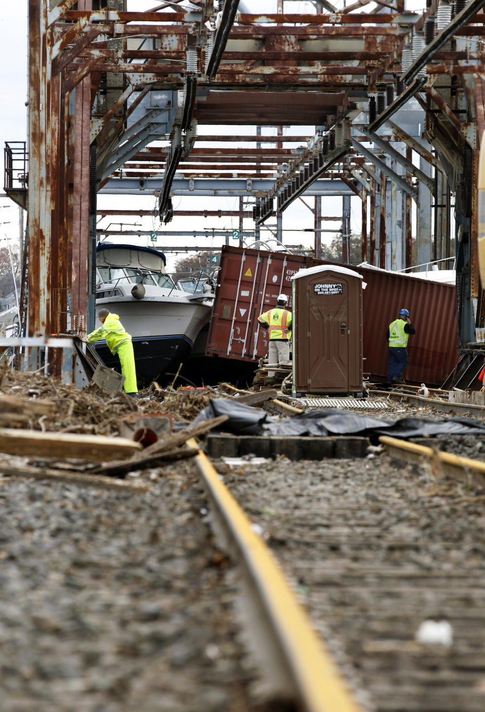 Workers try to clear boats and debris from the New Jersey Transit Morgan draw bridge Wednesday, Oct. 31, 2012, in South Amboy, N.J., after Monday's storm surge from Sandy pushed boats and cargo containers onto the train tracks. New Jersey Transit's North Jersey Coast Line, which provides train service from the New Jersey shore towns to New York City, may experience prolonged disruption. (AP Photo/Mel Evans)