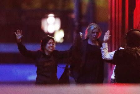 Hostages run towards a police officer (R) near Lindt Cafe, at Martin Place in central Sydney December 16, 2014. REUTERS/Jason Reed