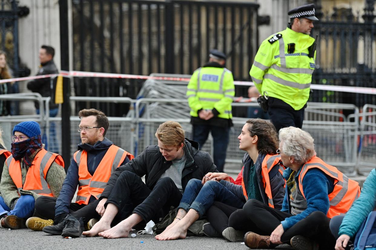 Police officers monitor environmental activists from the group Insulate Britain blocking a street at Parliament Square in central London on November 4, 2021, as they call for the UK government to fund the insulation of Britain's homes. - Insulate Britain, a new group whose campaigners have repeatedly blocked roads and motorways in and around the capital, want the government to insulate all British homes starting with social housing. (Photo by JUSTIN TALLIS / AFP) (Photo by JUSTIN TALLIS/AFP via Getty Images)