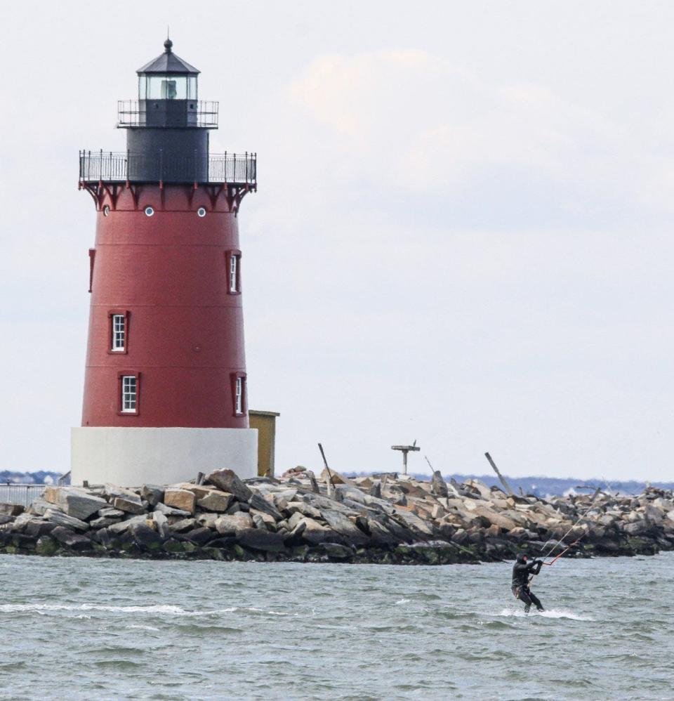 A man goes parasailing past the lighthouse at Cape Henlopen State Park.